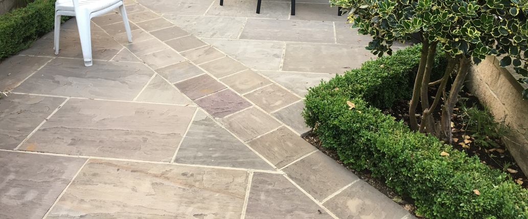 Autumn Brown Indian Sandstone paving in a warm and inviting outdoor seating area, showcasing its deep brown and chestnut tones with a naturally riven texture
