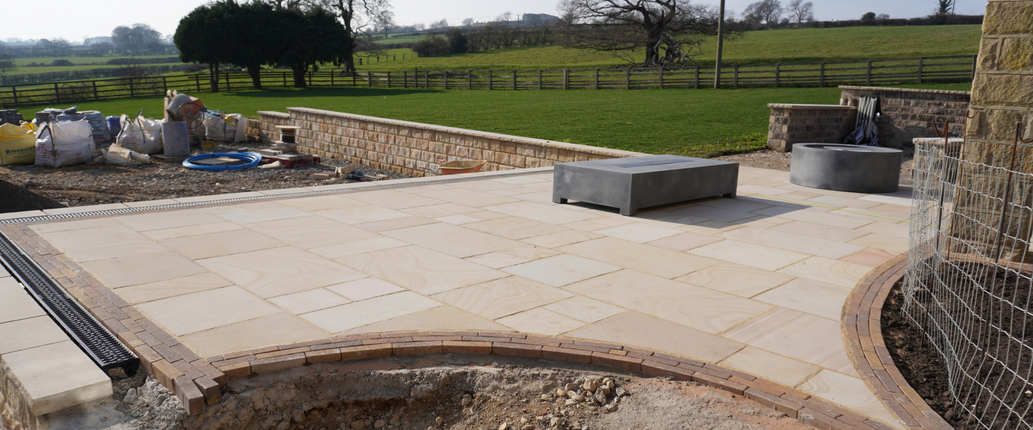 Golden Leaf Sawn Indian Sandstone patio with a smooth, honed surface and warm golden, beige, and ochre tones, creating a sleek and modern outdoor seating area.