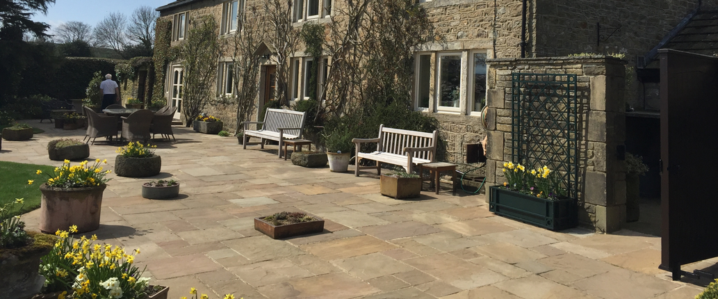 Old Manor Premium Indian Sandstone paving in a spacious outdoor seating area, showcasing its elegant mix of buff, grey, and subtle red tones with a tumbled finish