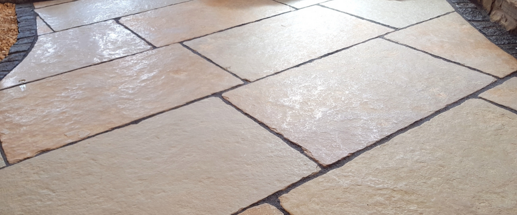 Regency Buff Limestone displayed in a showroom setting, showcasing its warm buff and golden tones with a smooth, aged weathered finish